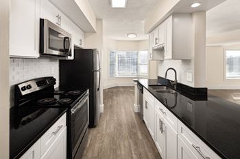 a kitchen with black counter tops and white cabinets